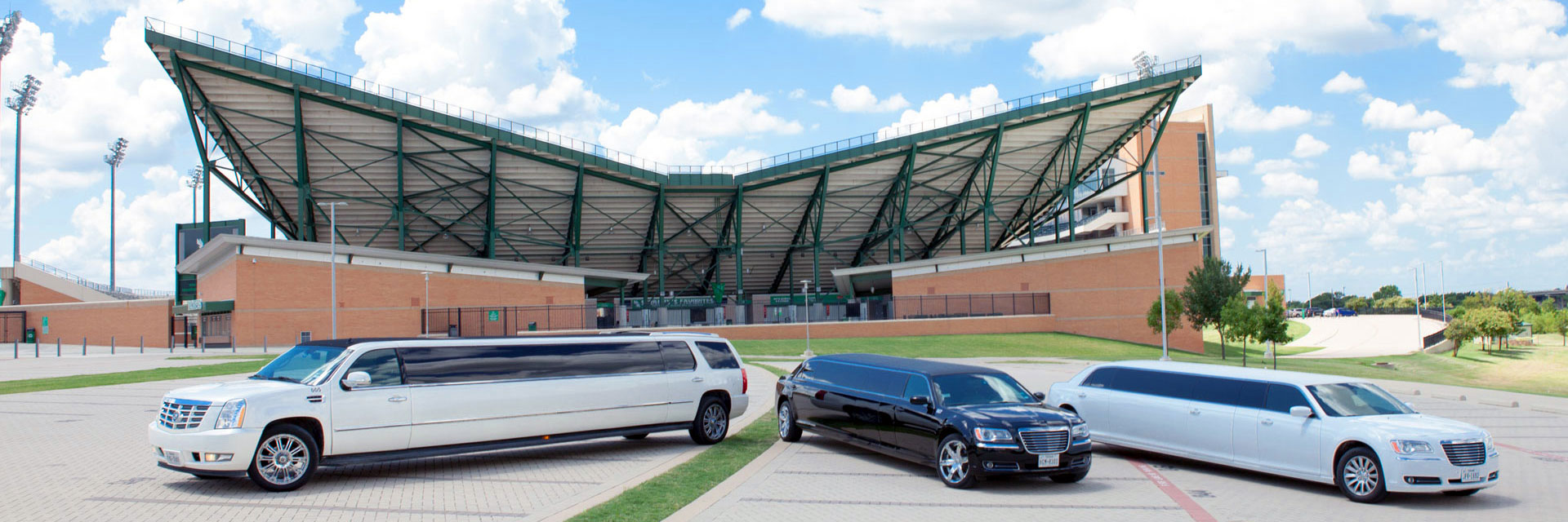 Three limousines parked outside a stadium.