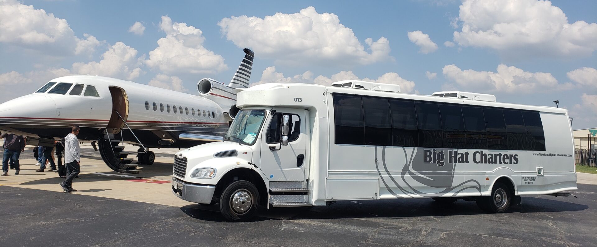 A big hat charters bus parked in front of a plane