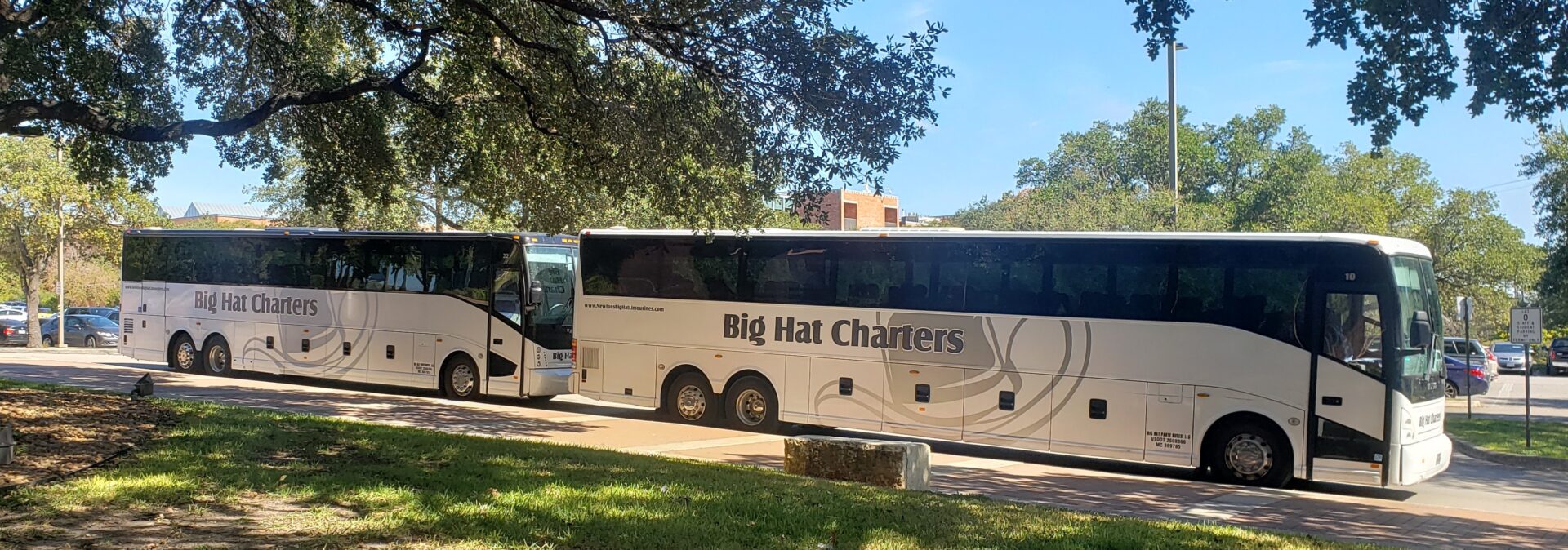 Two white Big Hat Charters buses parked.