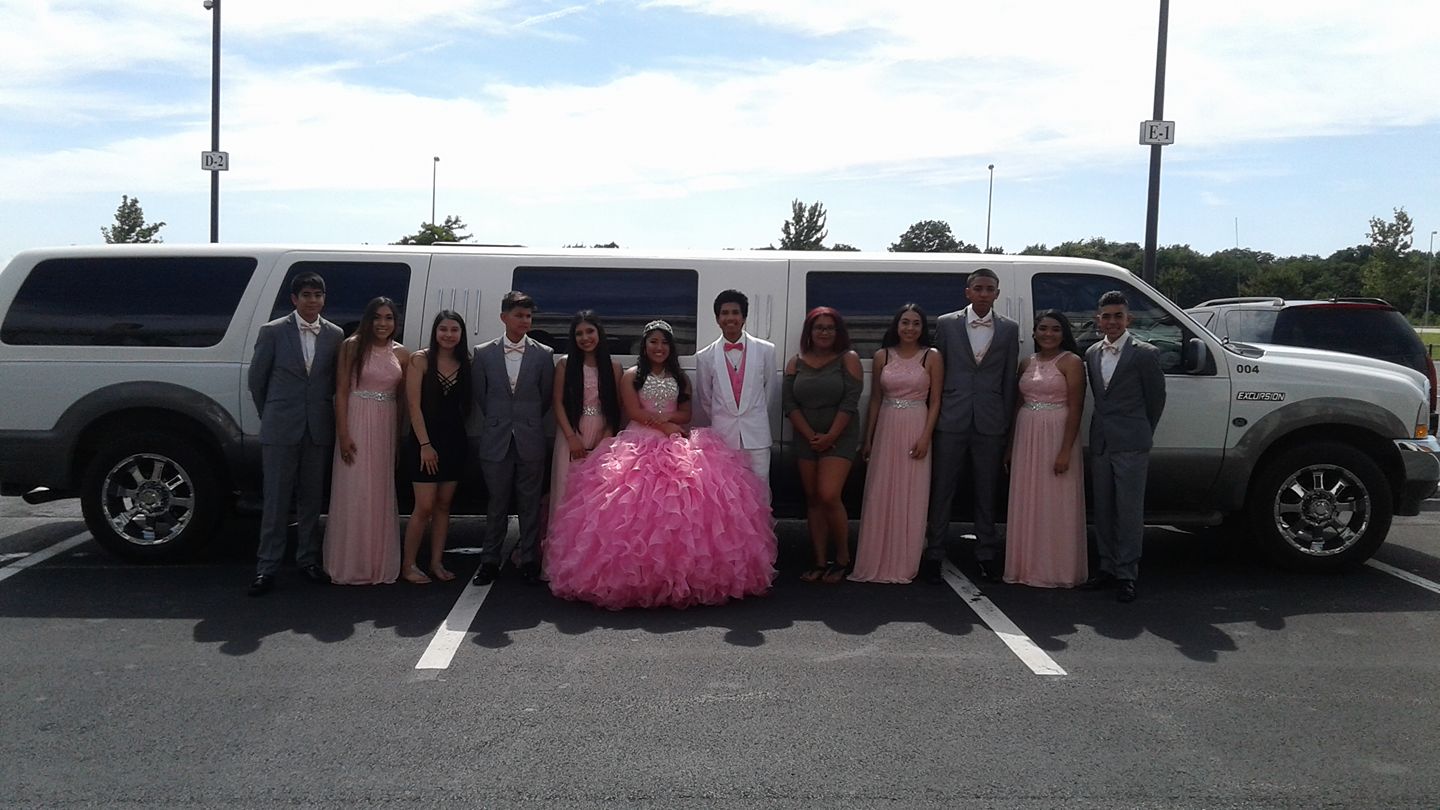 Group of people posing in front of a white limo.