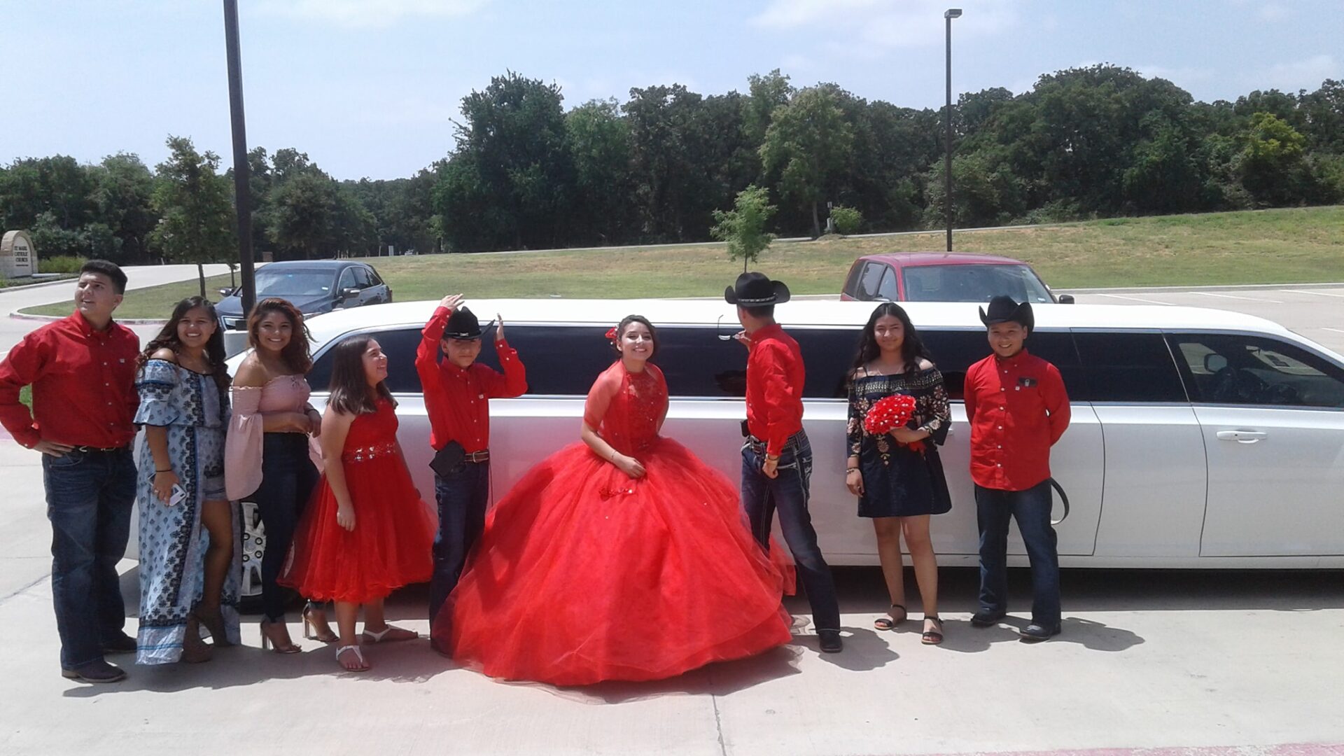 Group of people in red by a white limo.