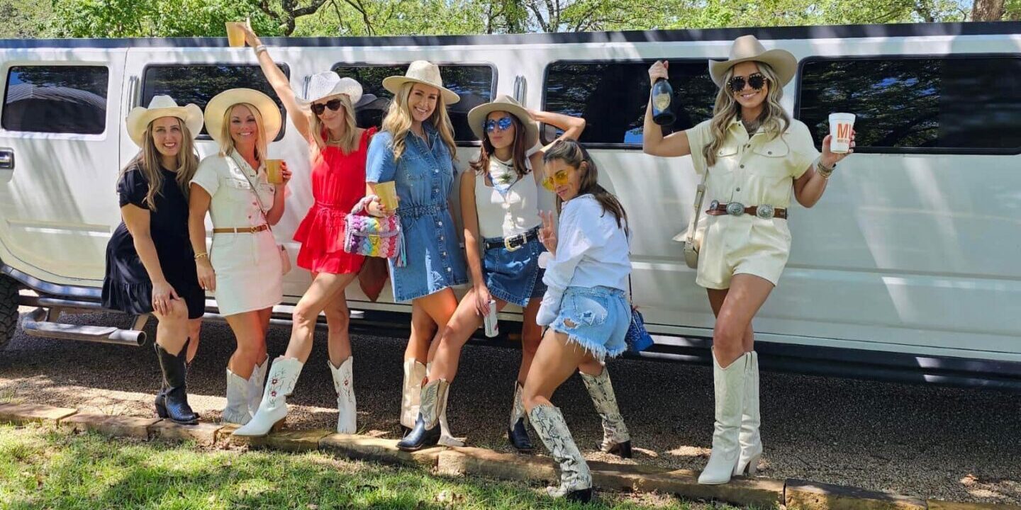 Six women in cowboy boots pose by a limo.